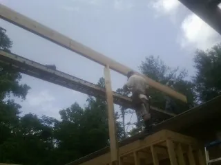 Carpenter setting a ridge beam over a new addition frame — Ice Dam Removal by Roofing Brothers in New Millport