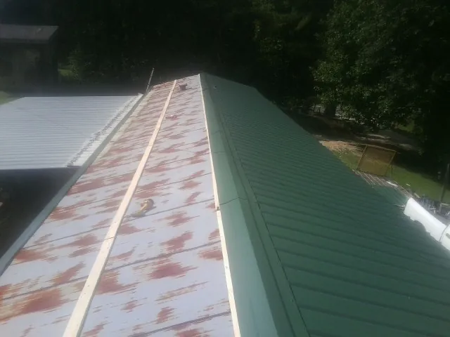 Old rusted panels beside newly installed green metal roofing — Wind Damage Roof Repair by Roofing Brothers in New Millport