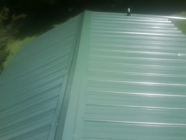 New green metal panels meeting at the ridge of a roof — Flat Roof Repair work by our crew in New Millport