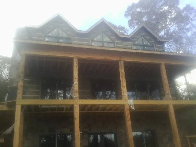 Dormers and porch framing on a large log home under construction — Roof Coating work by our crew in New Millport