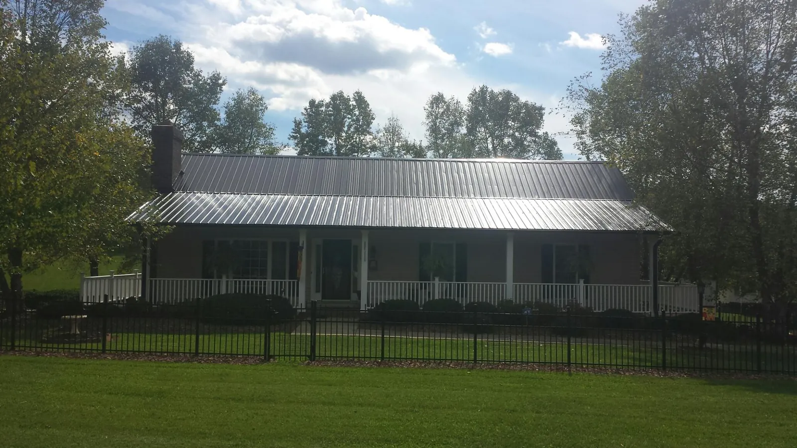 Gray metal roof on a brick ranch with a full width front porch — Gutter Guard Installation work by our crew in New Millport