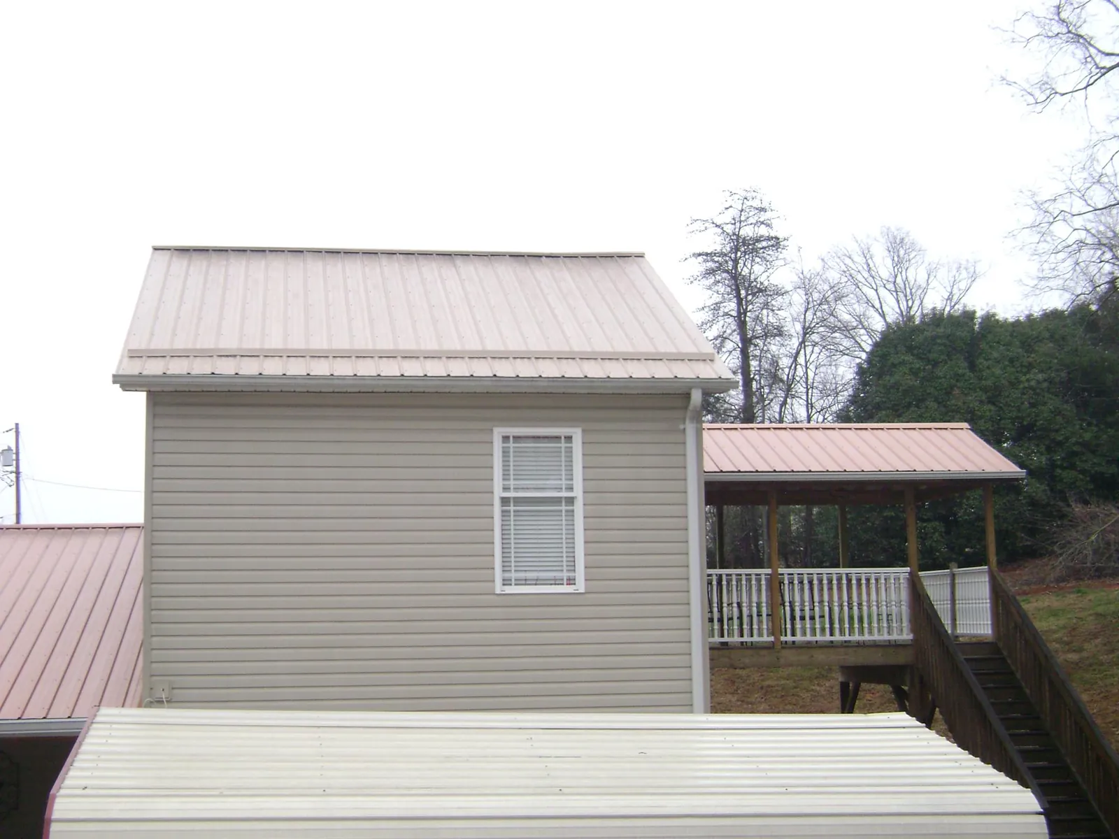 Tan metal roofs on a two story addition and attached porch, from a Roof Replacement job in New Millport