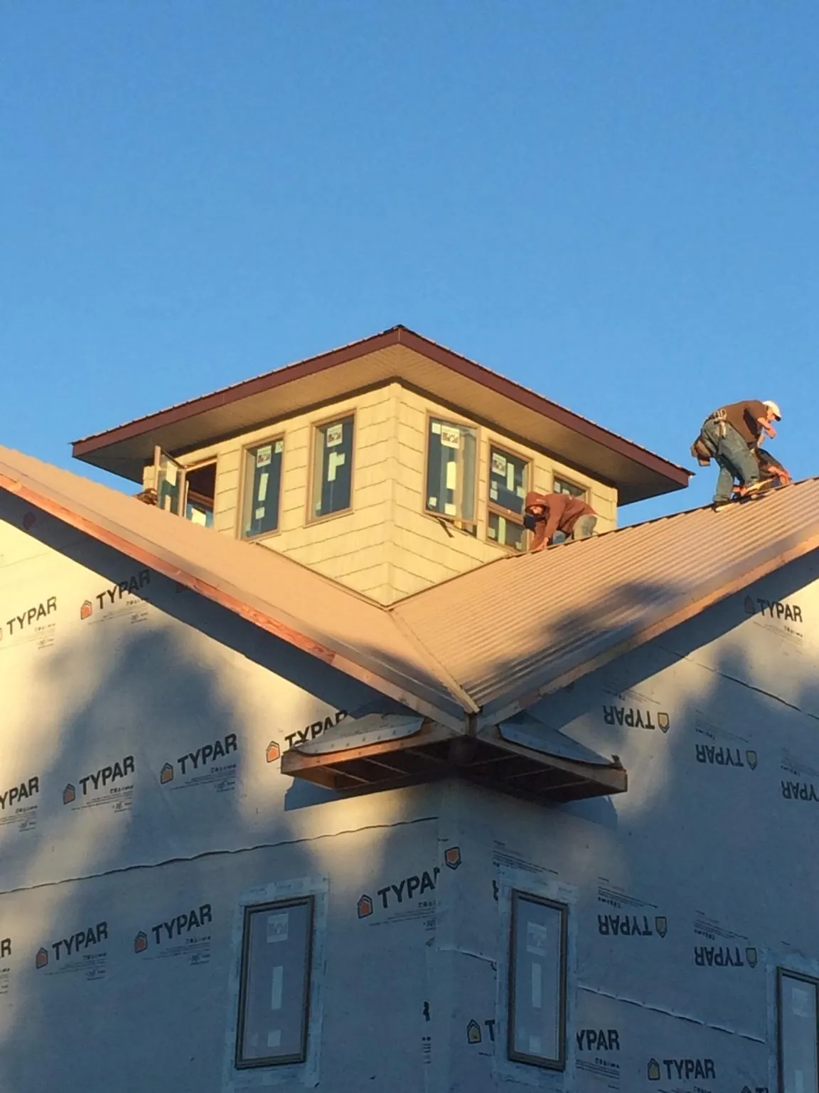 Roofers working around a rooftop cupola on a new metal roof at sunset — Roof Waterproofing in New Millport by Roofing Brothers